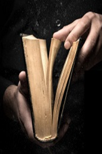 Cropped hands opening a book against black background 