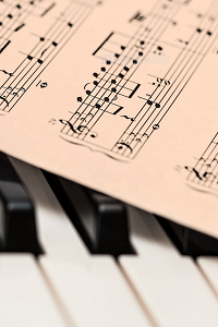 The keys of a piano are showing beneath a page of classical sheet music