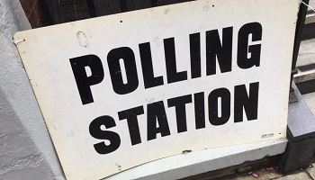 Polling station sign on railings outside building