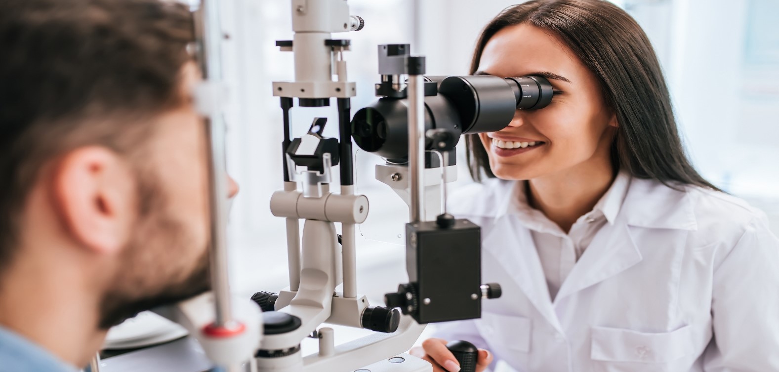 Female eye specialist examining male patient's eyesight 