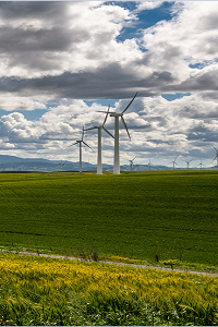 Green fields with wind turbines, low clouds and some blue sky 